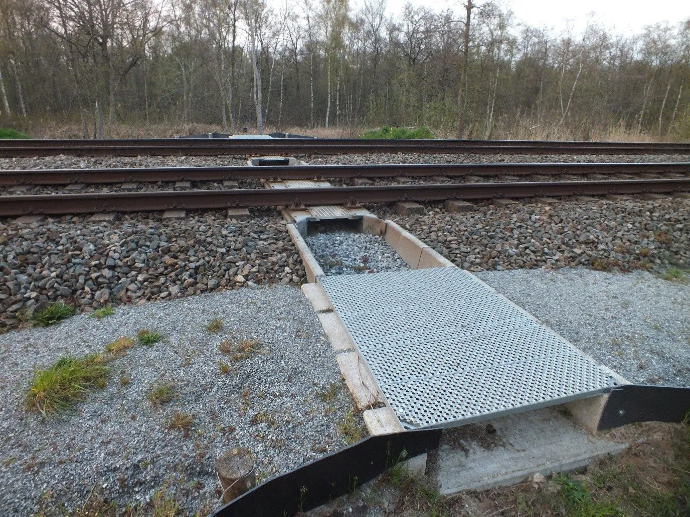 Entrance to the fauna passage with grating deck and guide walls beside the track