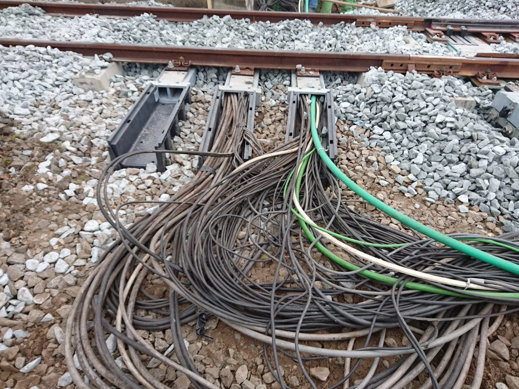Cables being pulled through three hollow steel Kampa Sleepers, with coils of cable on the ballast