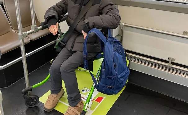 A passenger seated on their own rollator inside a tram, the wheels held by the floor guide