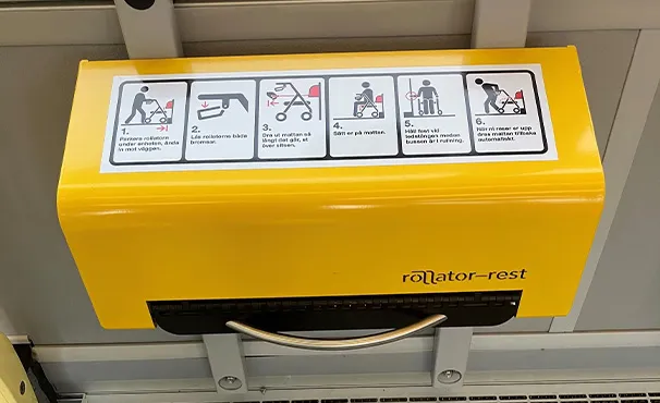 A yellow Rollator-Rest unit mounted in a tram, with step-by-step instructions on the cover